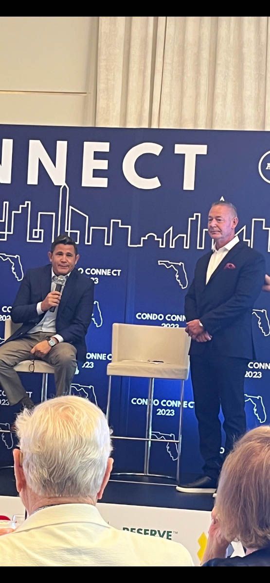 Two men are standing in front of a sign that says connect.