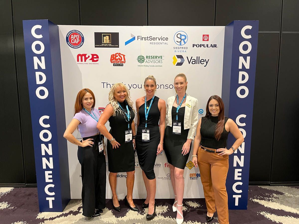 A group of women are posing for a picture in front of a wall that says condo connect.
