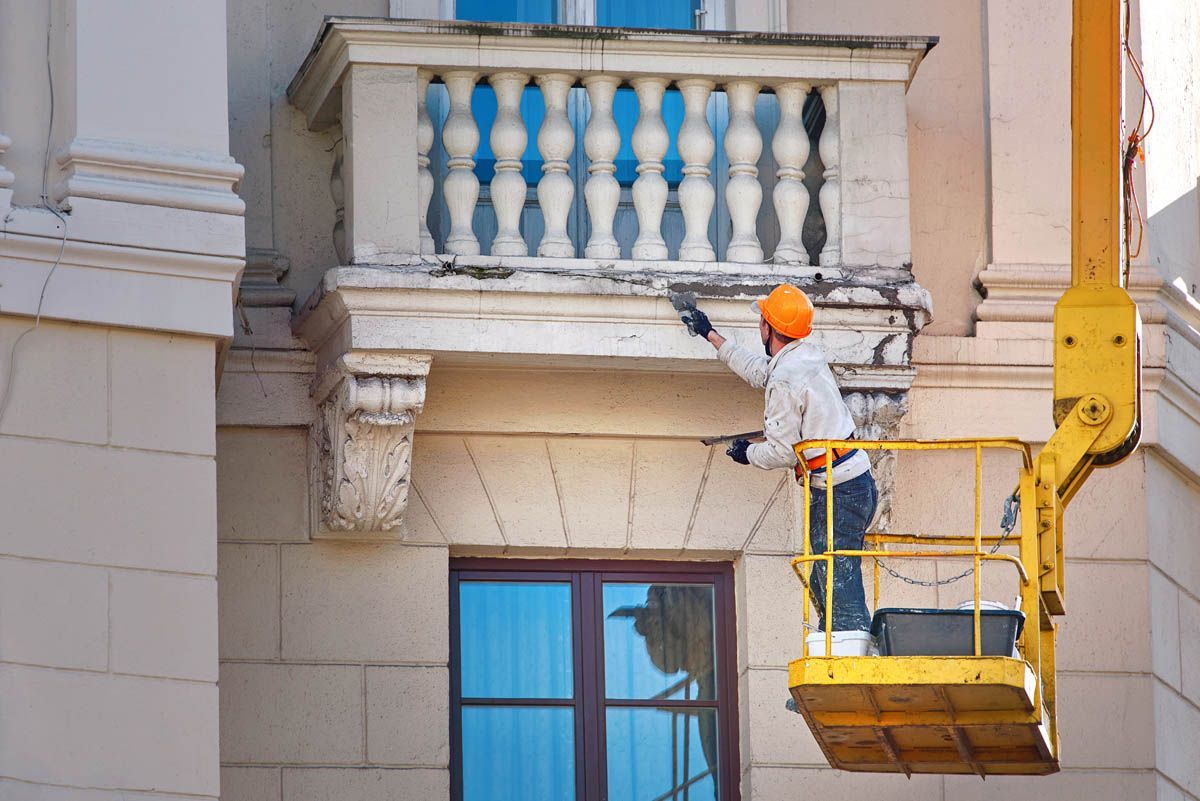A man is painting a balcony on a building.