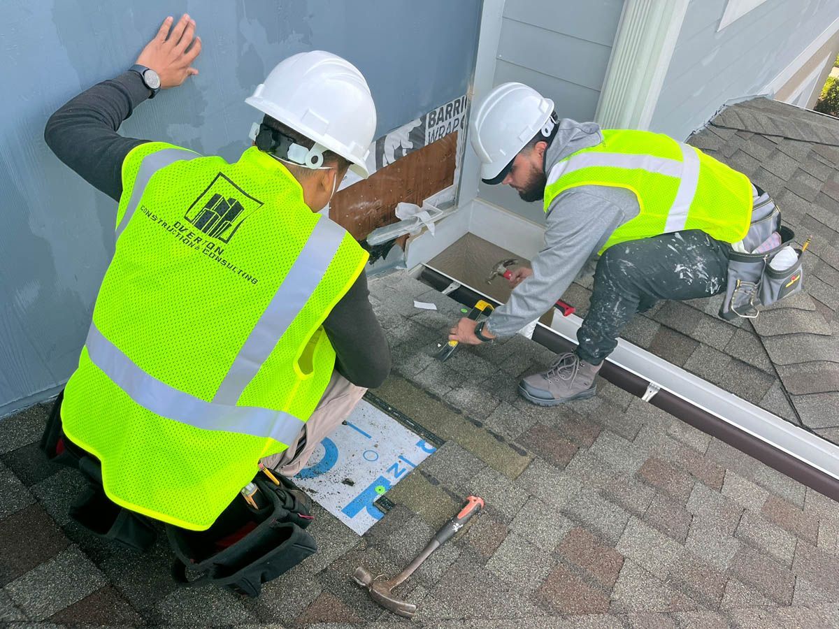 Two construction workers are working on a roof.