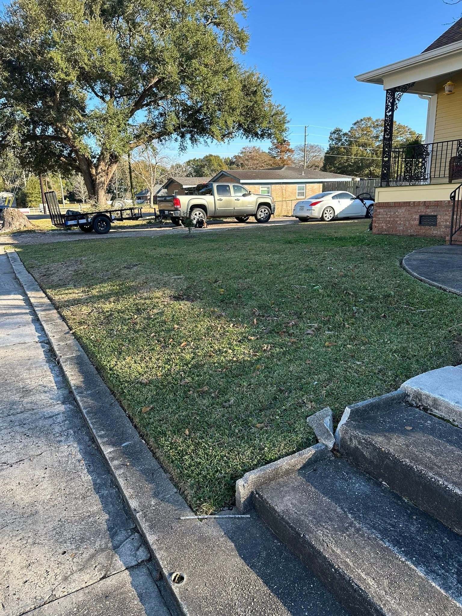 A view from a porch looking down onto a grassy lawn, with a pickup truck and a sedan parked in the background.