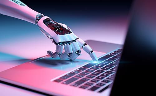 A robotic hand is typing on a laptop computer.