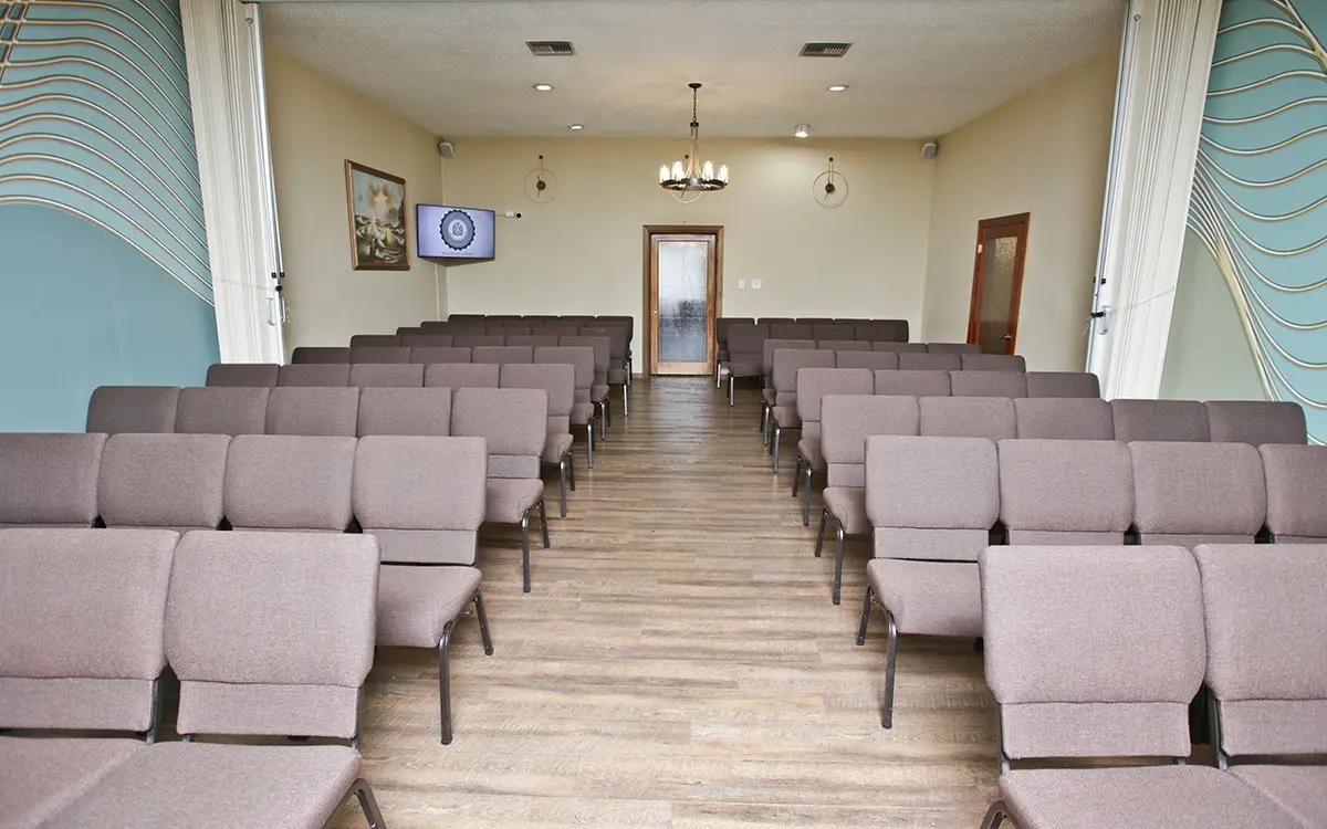Rows of brown chairs face a door, in a beige and blue room.