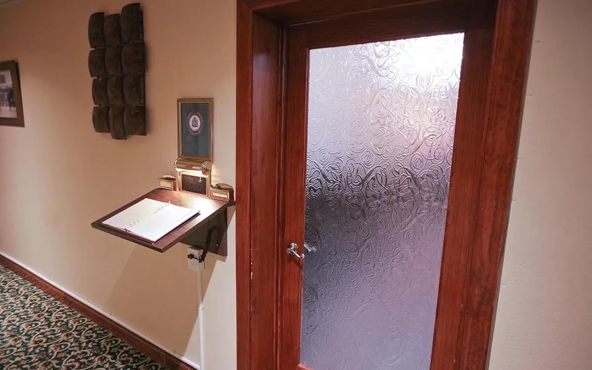 Dark wooden door with frosted glass panel; wall-mounted desk.