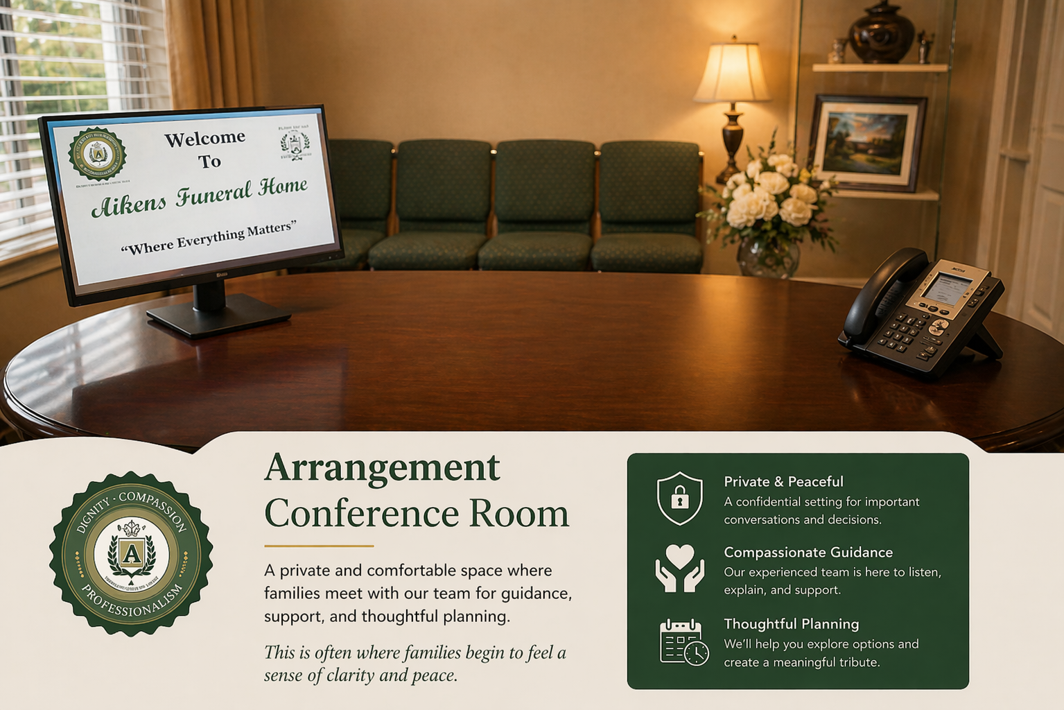 Conference room with polished table, green chairs, wall TV, lamp, flowers, and an arrangement sign.