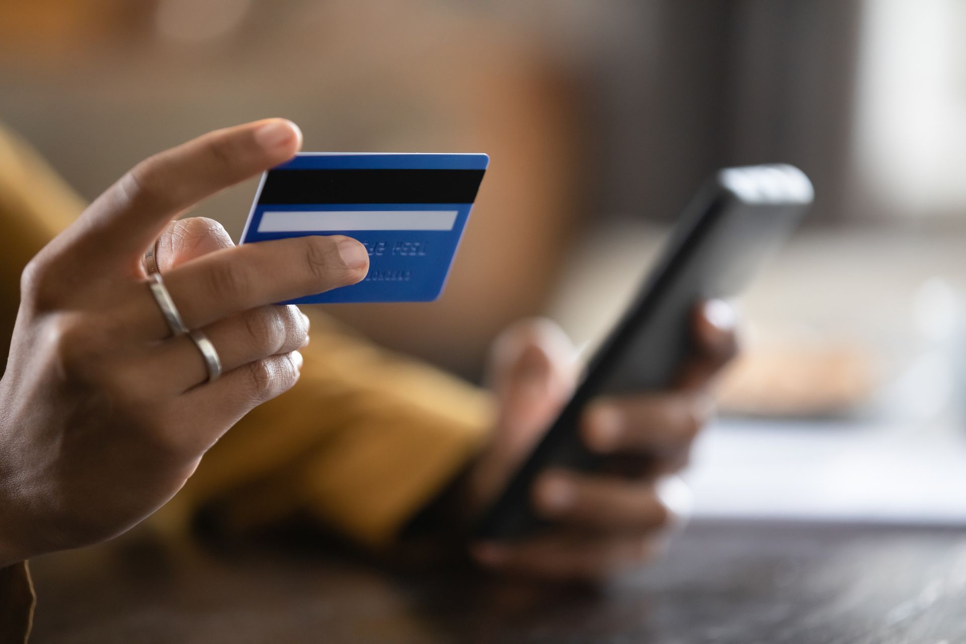 Woman holding a credit card and smartphone, possibly making an online payment.