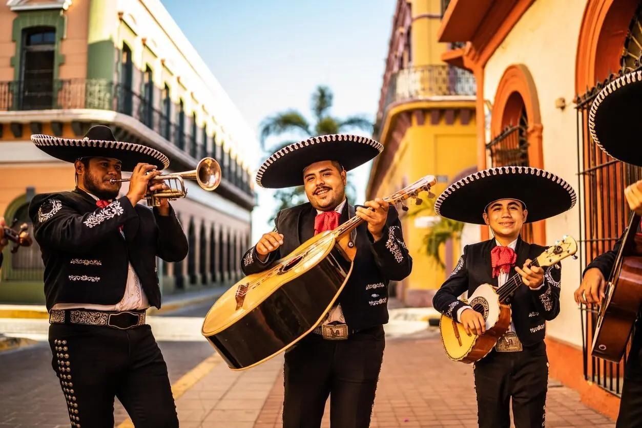 Mariachi band playing instruments, wearing red and white suits.