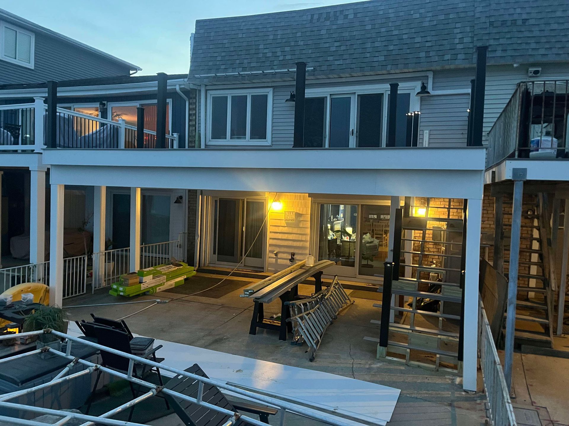 Backyard patio with string lights, outdoor seating, and a lit house exterior at dusk