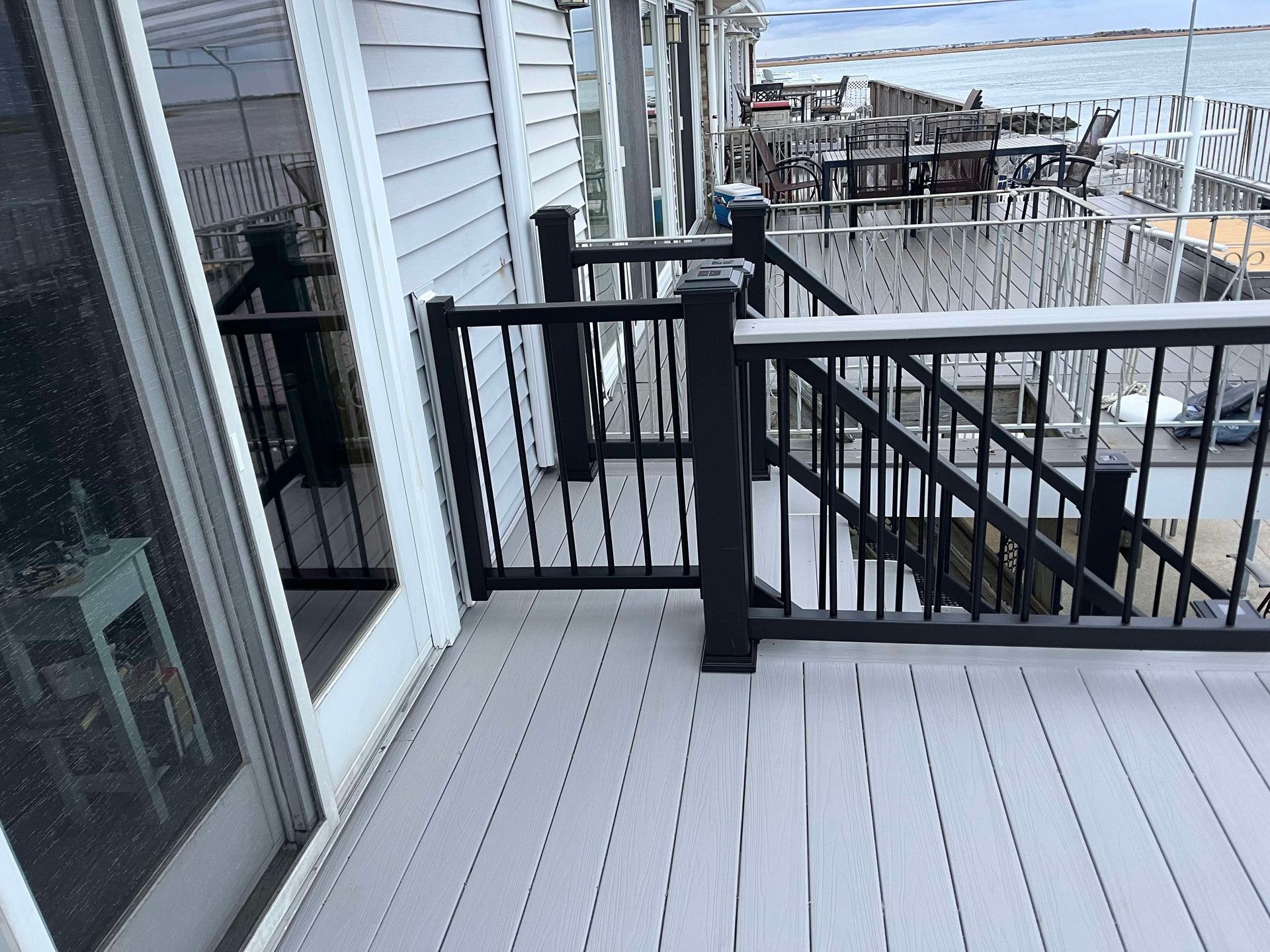 Snowy deck with black railing beside a house, overlooking a winter neighborhood.