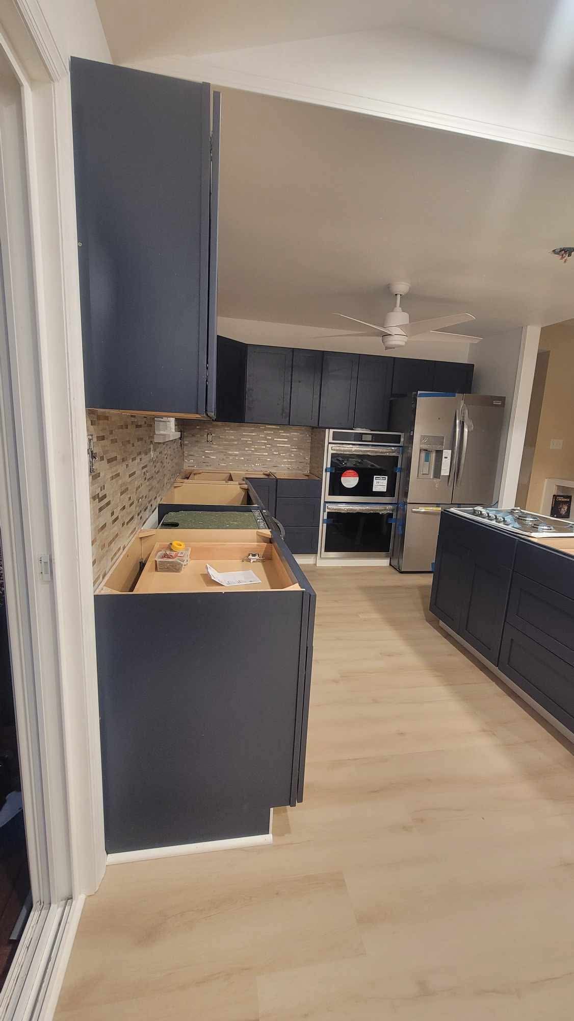 Modern kitchen with dark cabinets, wood floor, and stainless steel appliances.