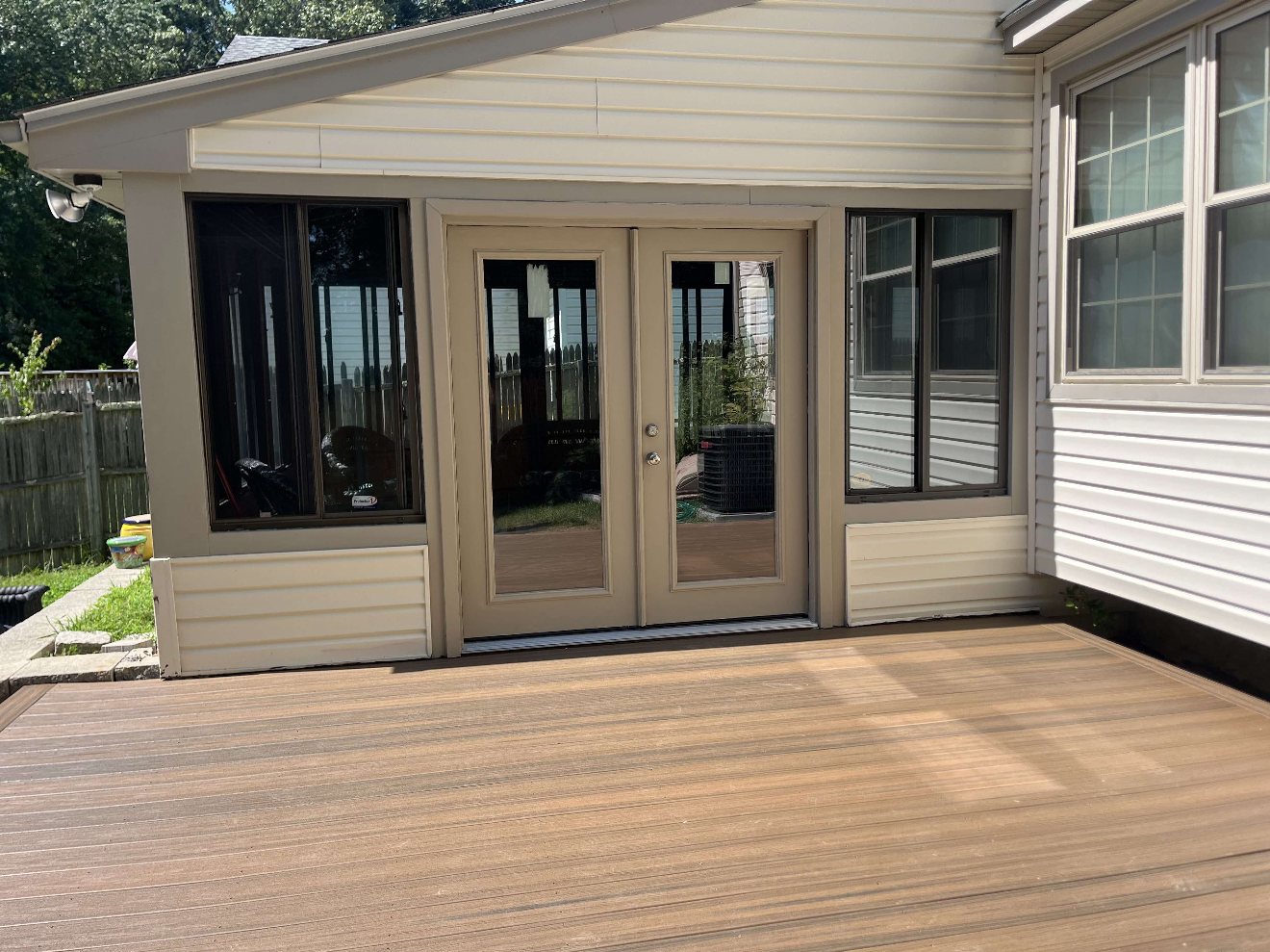Backyard deck with sliding glass doors and a tan house exterior.