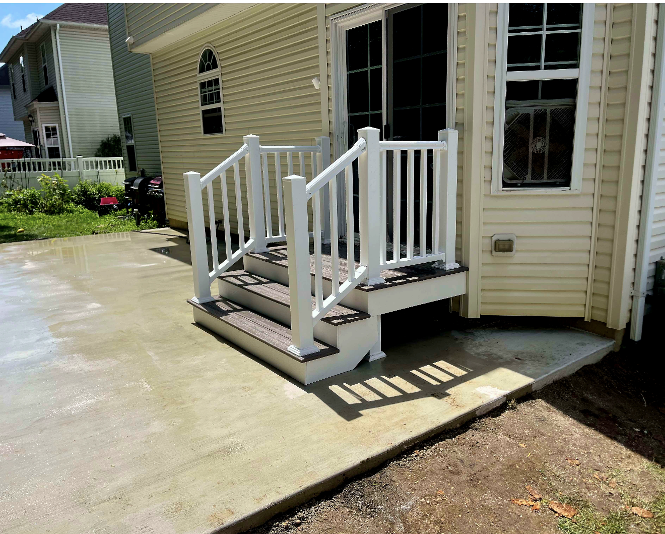 Small white wheelchair ramp and steps leading to a beige house entrance on a concrete patio