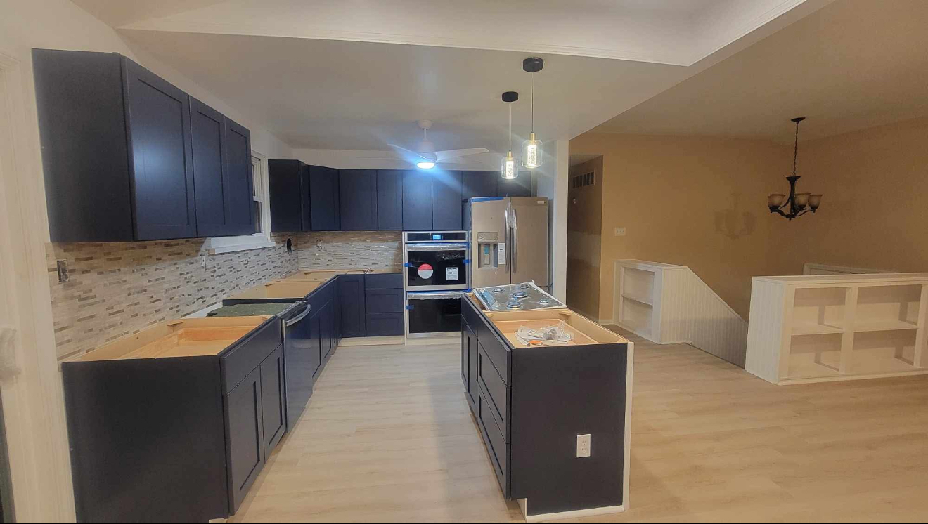 Open-plan kitchen with dark cabinets, island, and light wood floors in a modern home