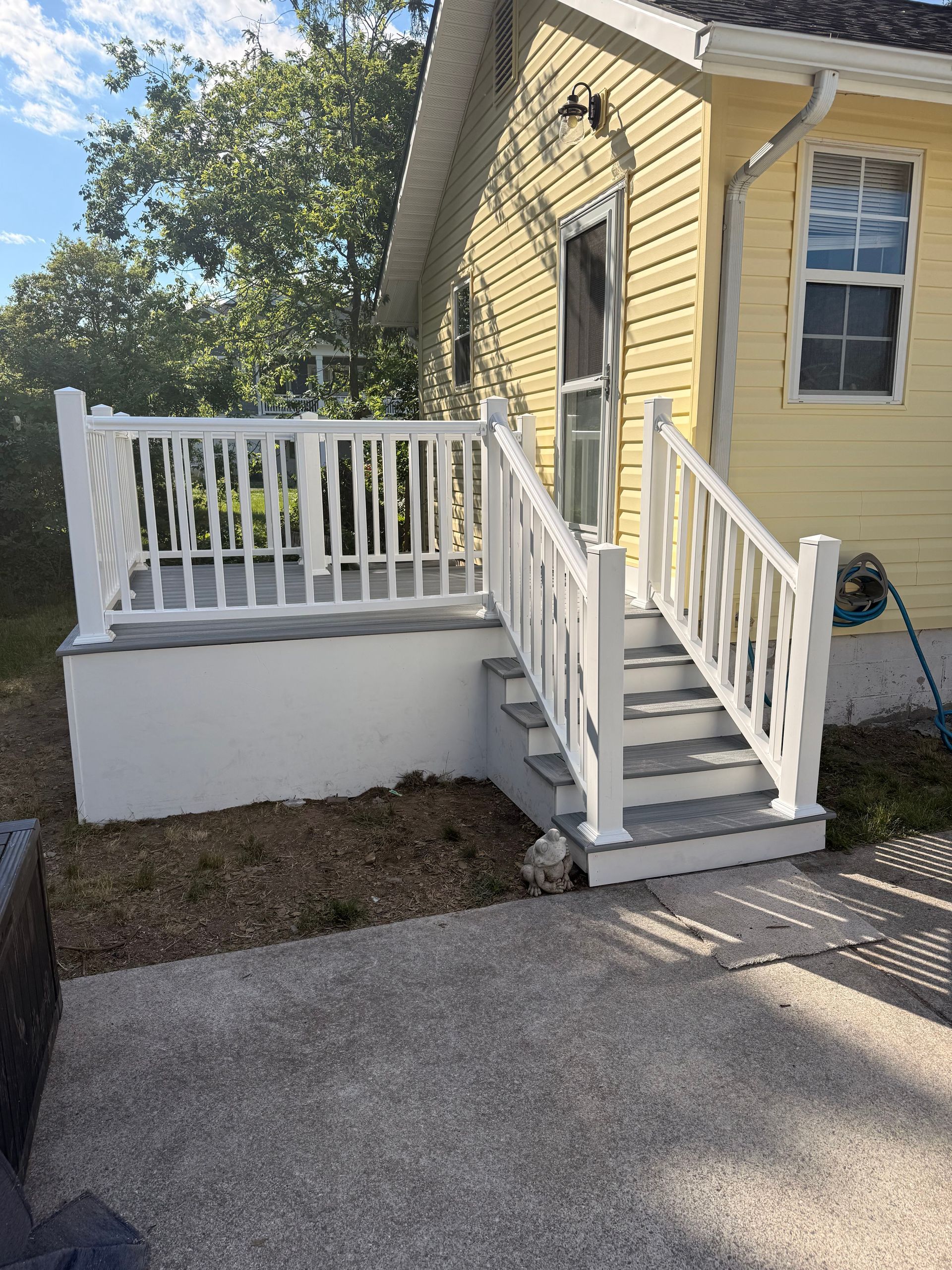 Yellow house entrance with white ramp, railing, and steps leading to a small porch