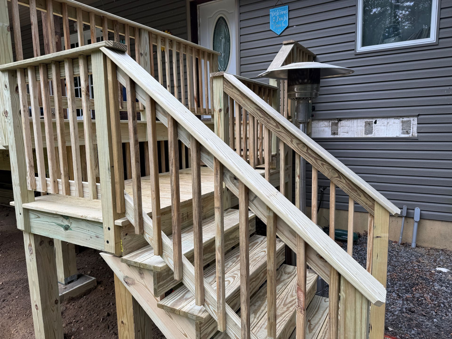 Wooden outdoor staircase and porch railings beside a house with gray siding
