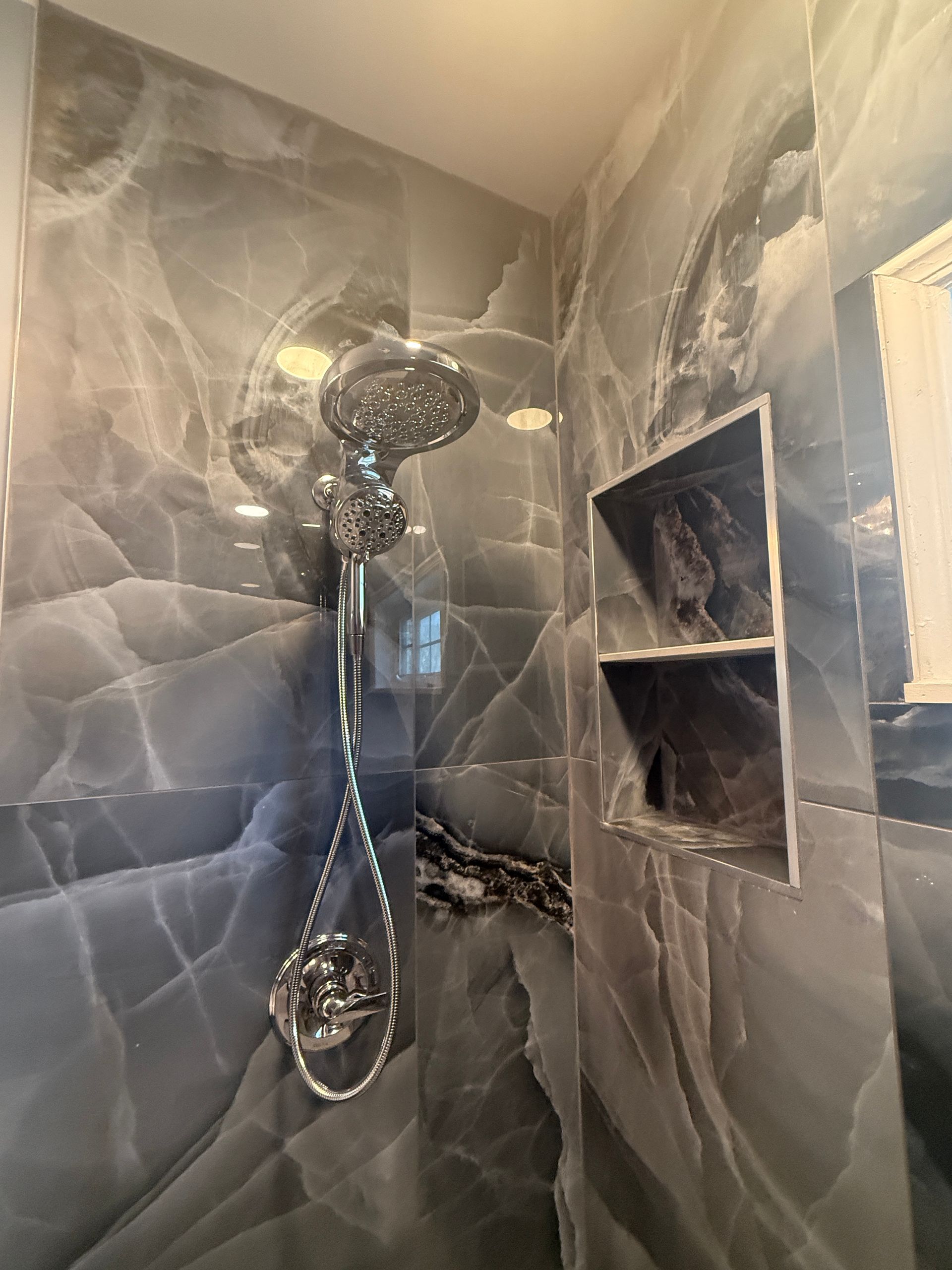 Modern tiled shower with chrome showerhead and built-in wall niche shelves