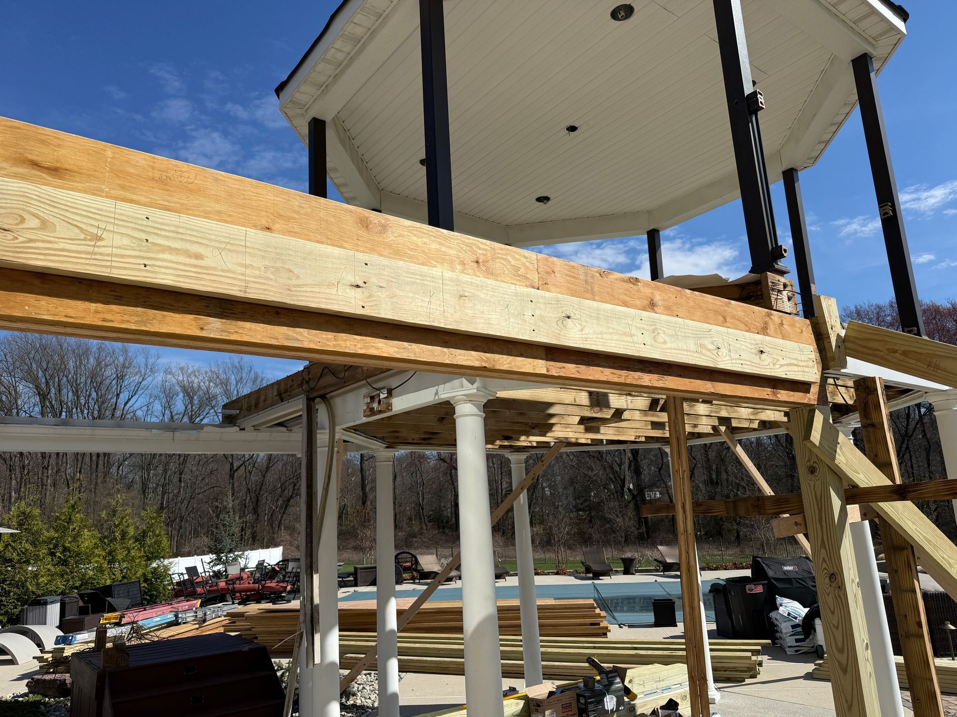 Partially built wooden deck framing beneath a round white structure outdoors