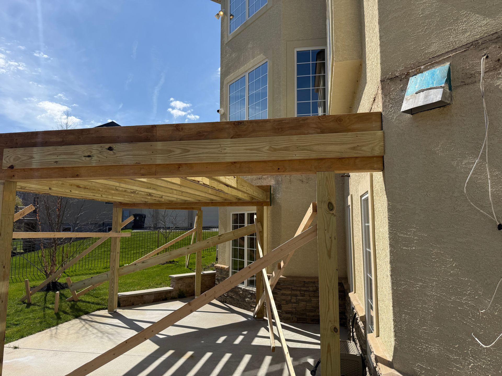 Wooden scaffolding and braces beside a stucco house under construction on a sunny day