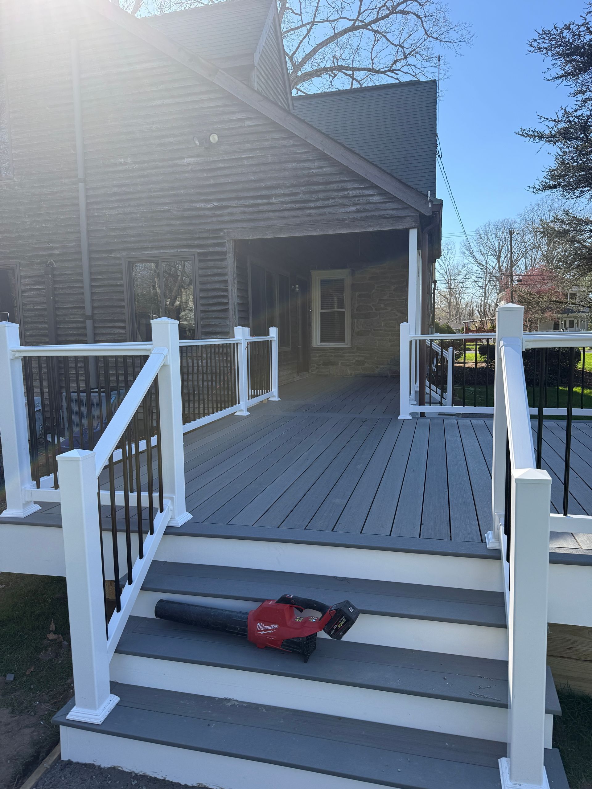 Front porch with white railings and steps leading to a dark house; a red toy car sits on the stairs.