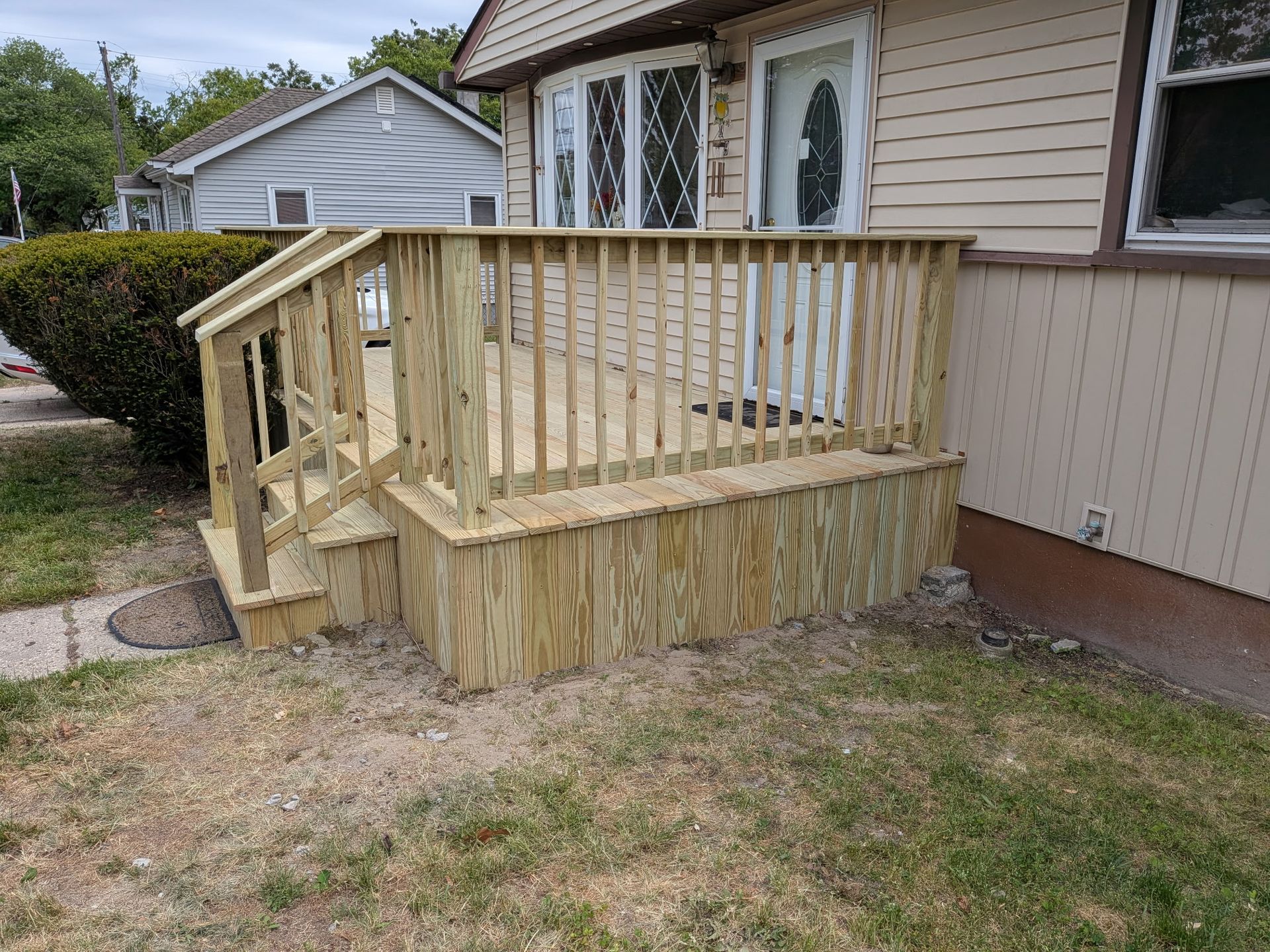 Wooden wheelchair ramp with railing leading to a beige house entrance