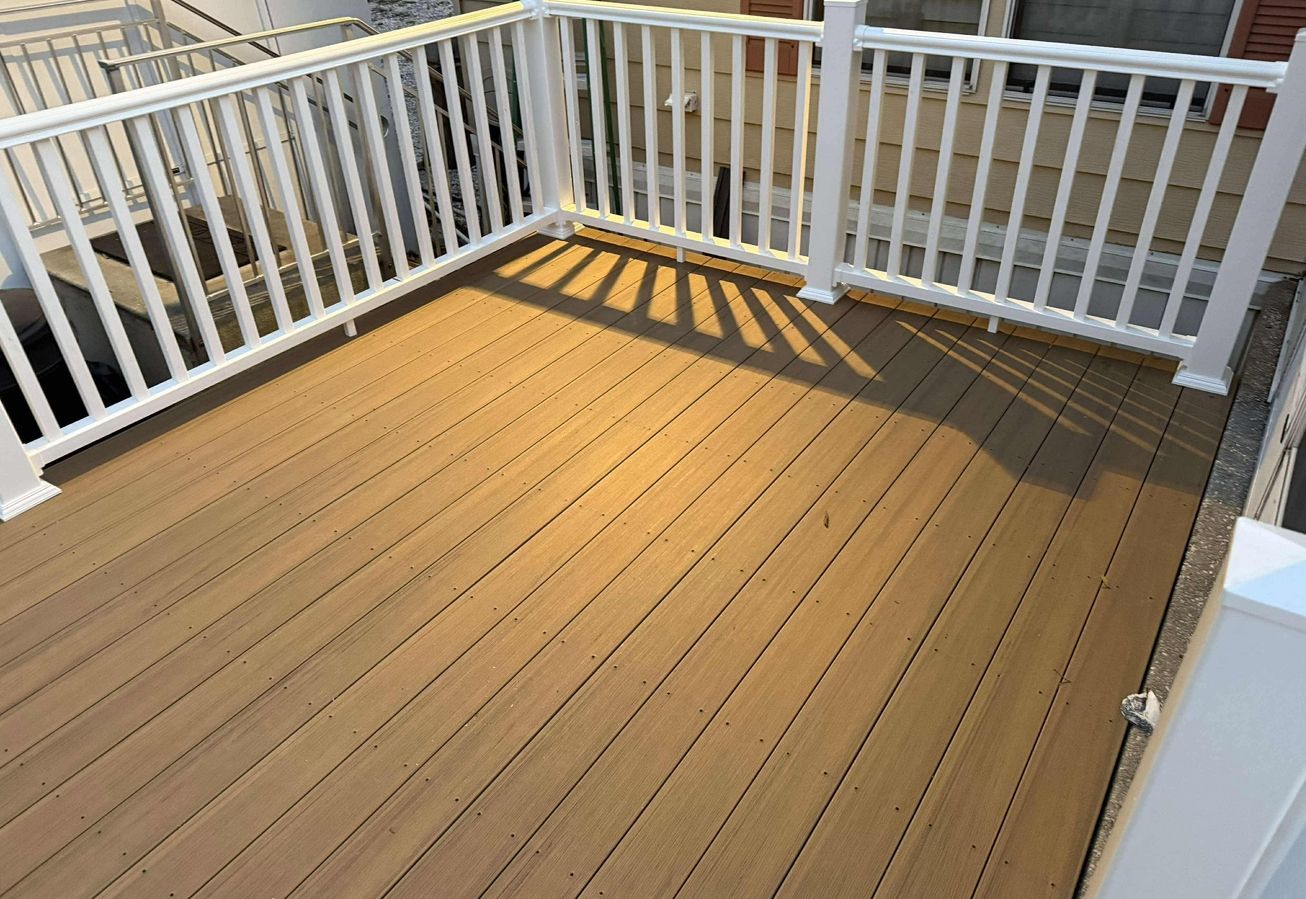 Small tan deck with white railings and sunlight casting shadows on the floor