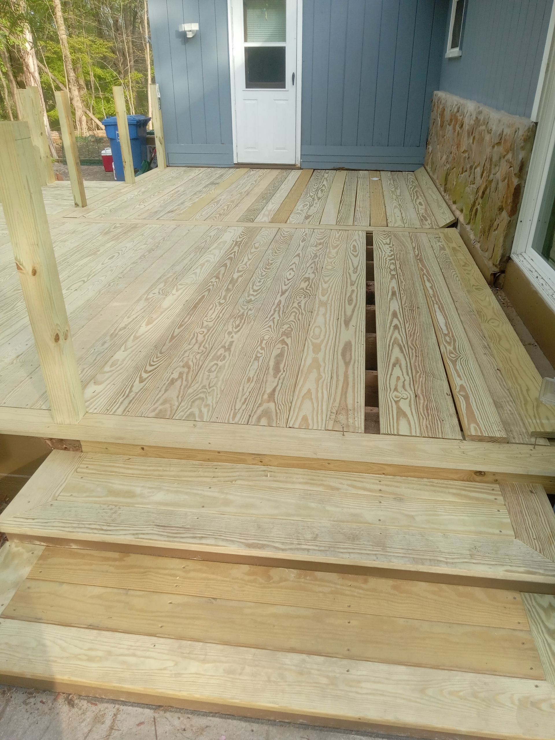 Wooden ramp leading to a blue door on a house porch