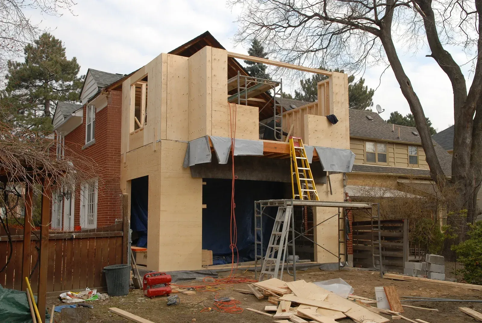 House under construction: wooden frame extension being added to a red brick building.