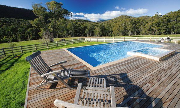 A Large Swimming Pool Is Surrounded By A Wooden Deck And Chairs — Mediterranean Custom Pools In Kialla, VIC