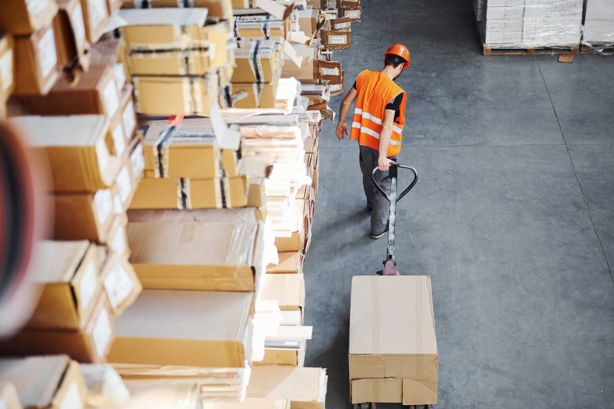 A distribution center employee pulling a crate on a cart near a large stack of crates at C & S Transportation near Nicholasville, Kentucky (KY)