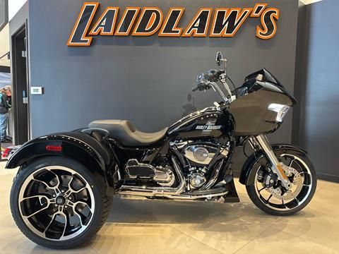 Black three-wheeled motorcycle parked indoors in front of a Laidlaw’s sign