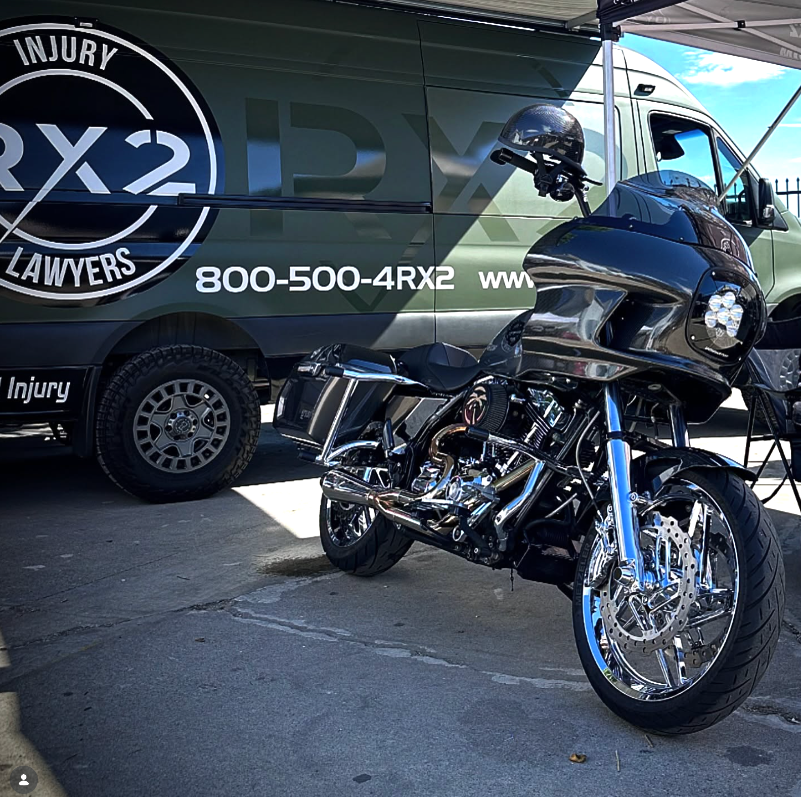 Black motorcycle parked in front of a 4RX2 Lawyers van with a large injury-law logo.