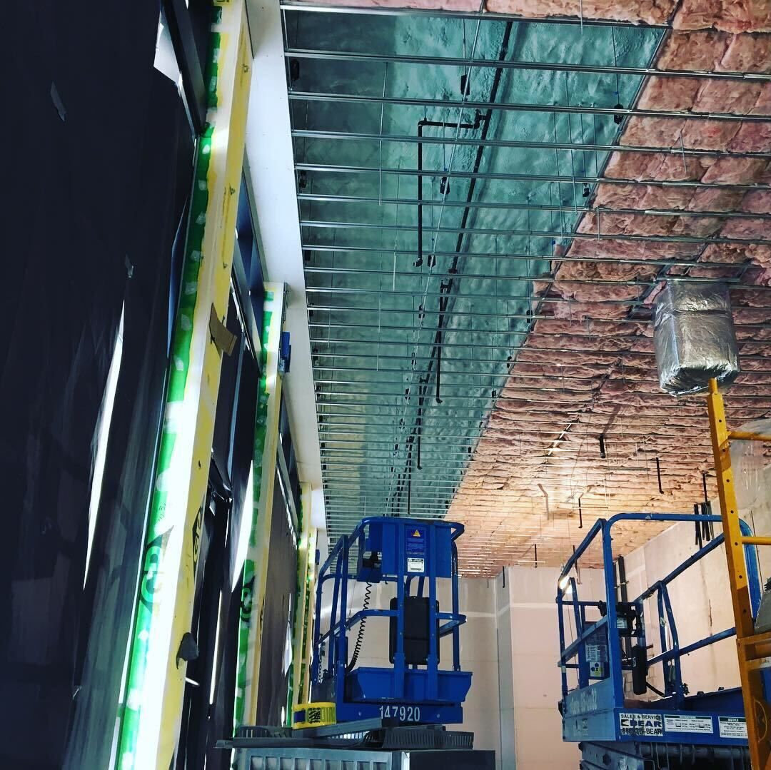 Construction scaffolding in a narrow corridor with exposed ceiling insulation and hanging lights
