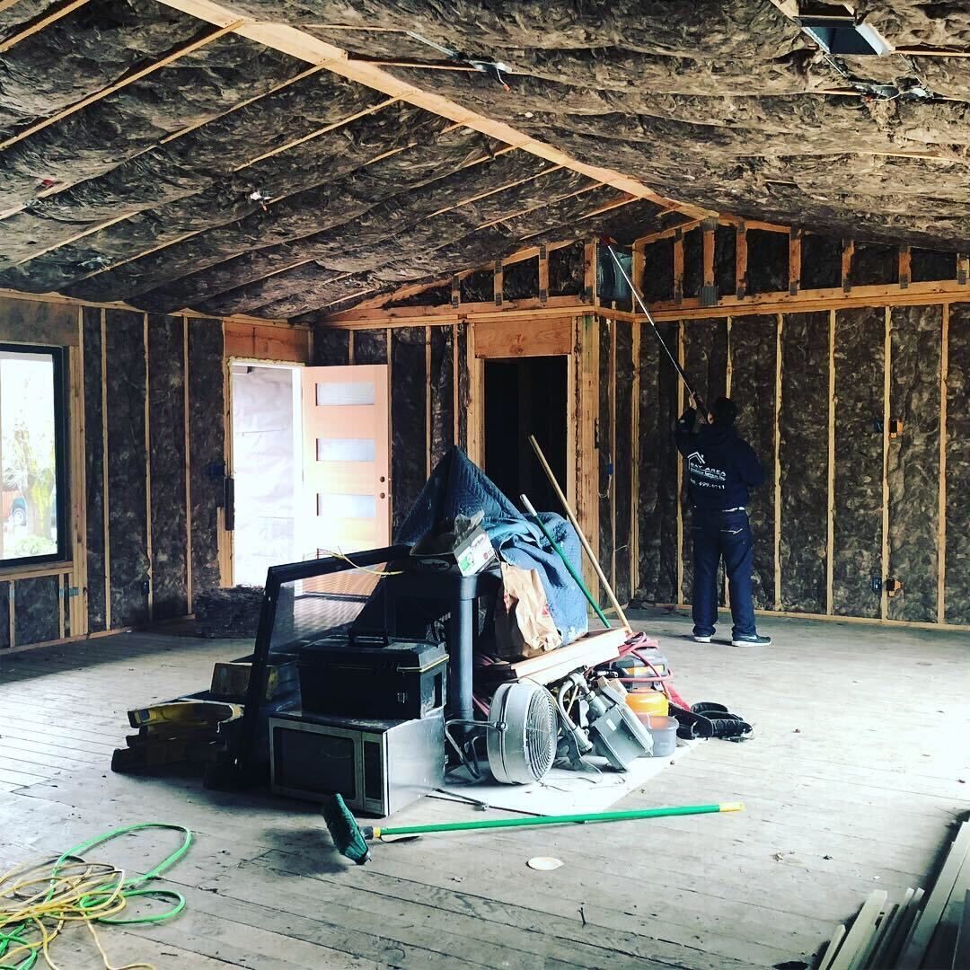 Unfinished room with exposed insulation, two windows, and bare walls under construction