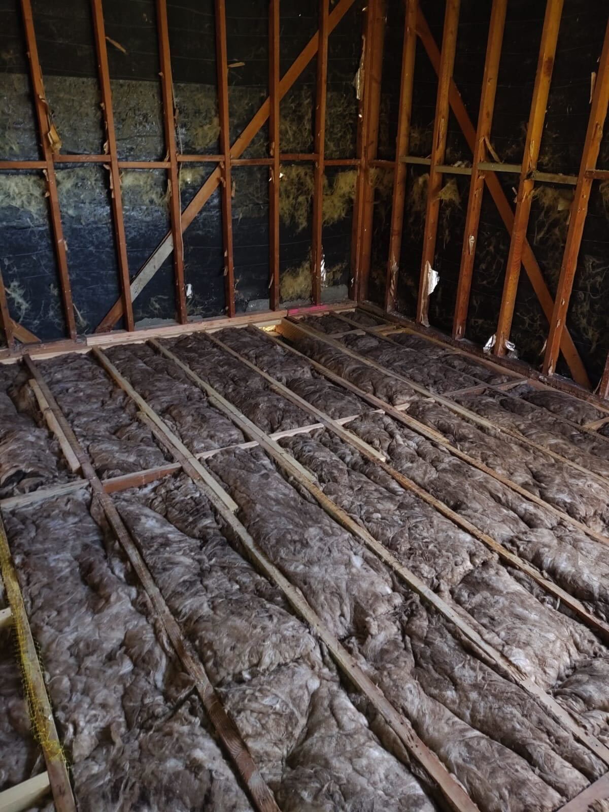 Rusty metal bars enclosing a dim, unfinished wooden and dirt floor space