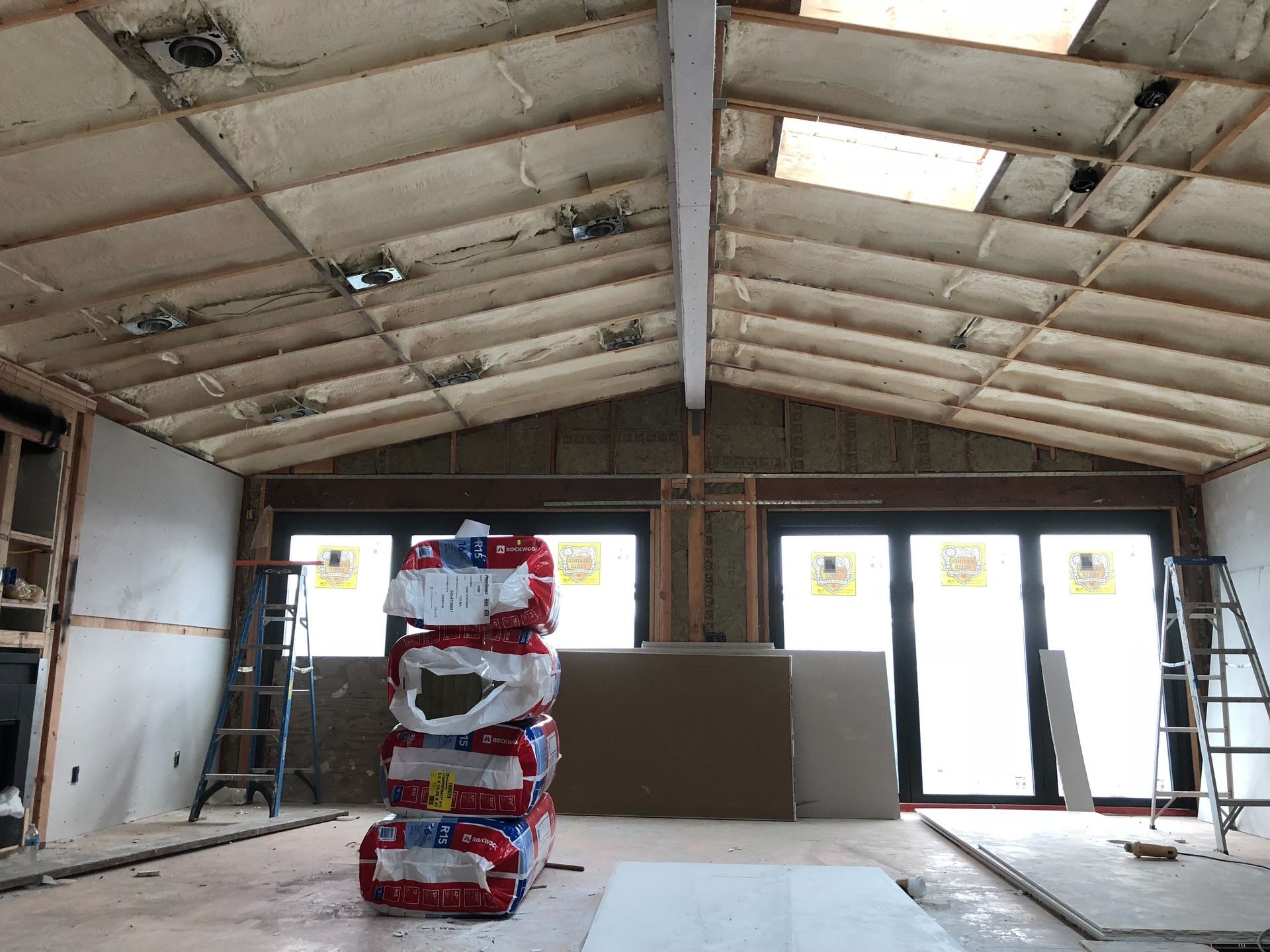 Unfinished room with exposed insulation, two windows, and bare walls under construction