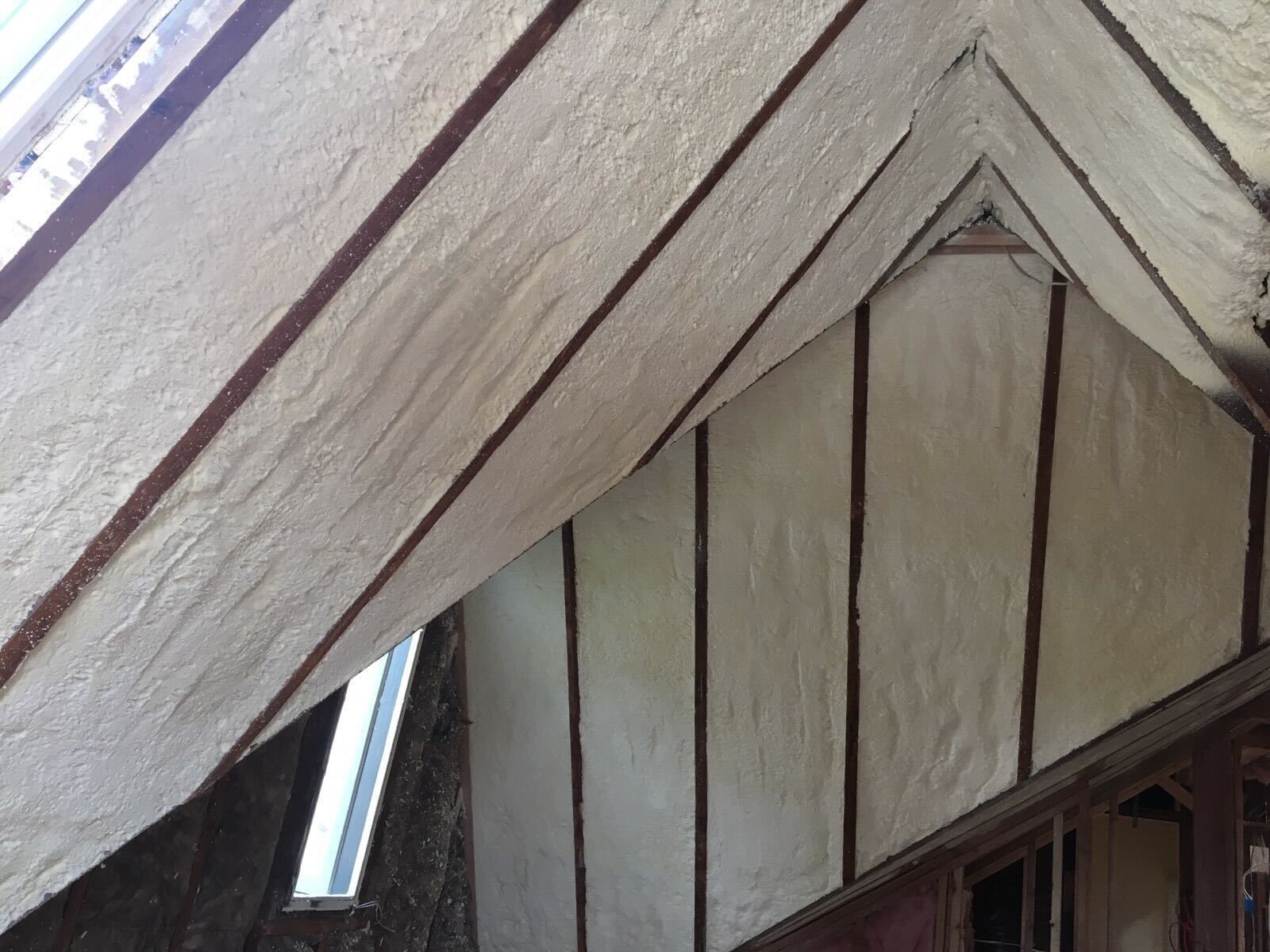 Close-up of a wooden roof gable with diagonal beams and a small window beneath it
