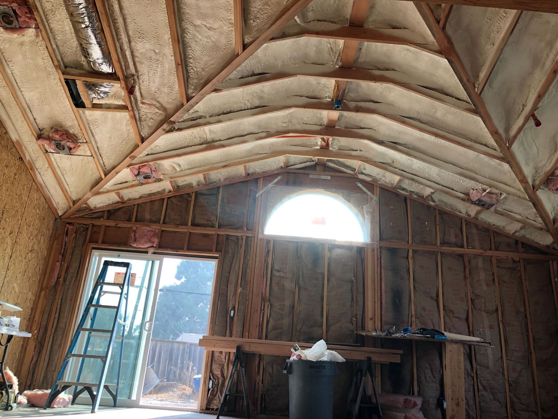 Unfinished room with exposed insulation, two windows, and bare walls under construction
