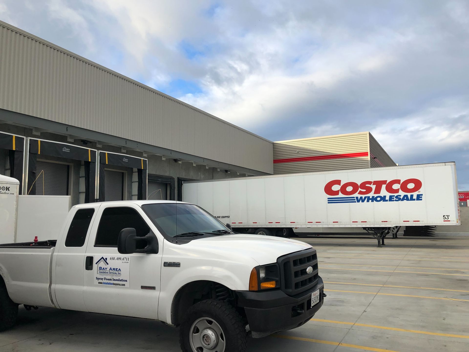 White truck parked outside Costco Wholesale loading dock under cloudy sky