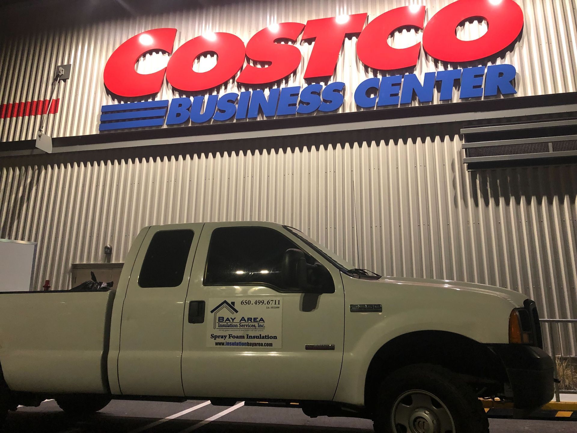 White pickup truck parked in front of a Costco Business Center storefront at night