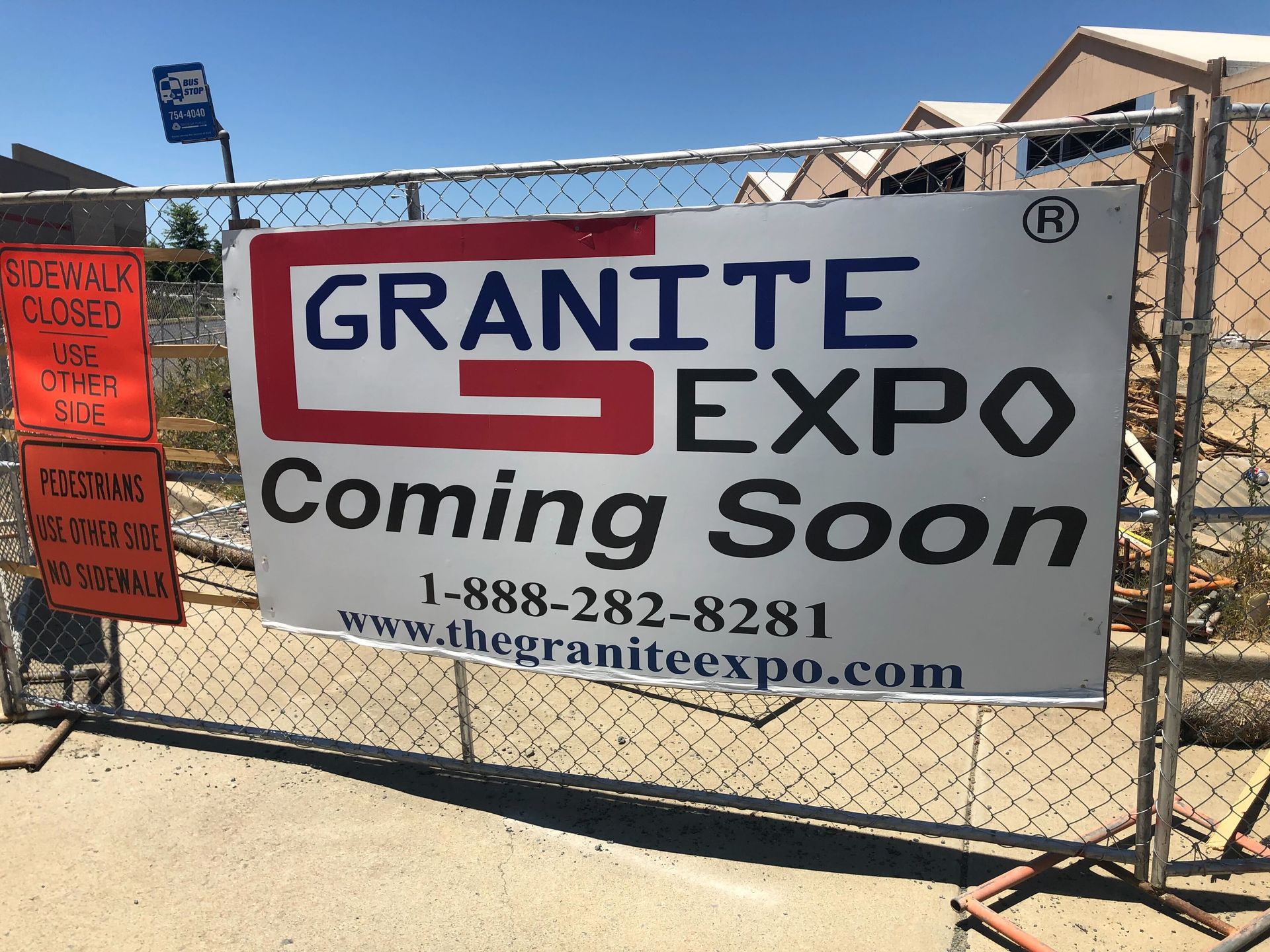 Banner on fence reads “Granite Expo Coming Soon” with website and phone number under a blue sky.