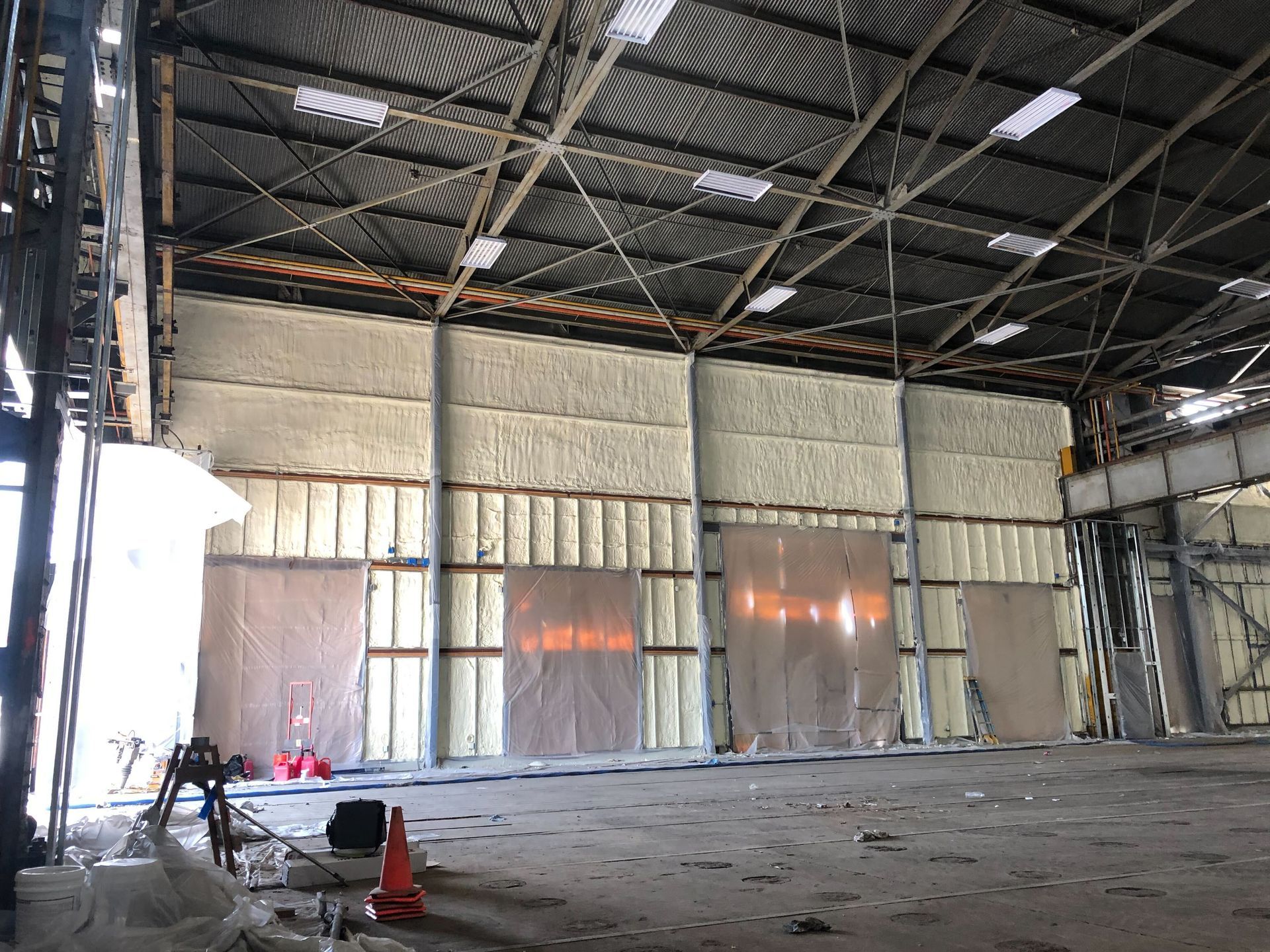 Empty industrial warehouse with a metal roof, concrete floor, and tall corrugated walls under construction