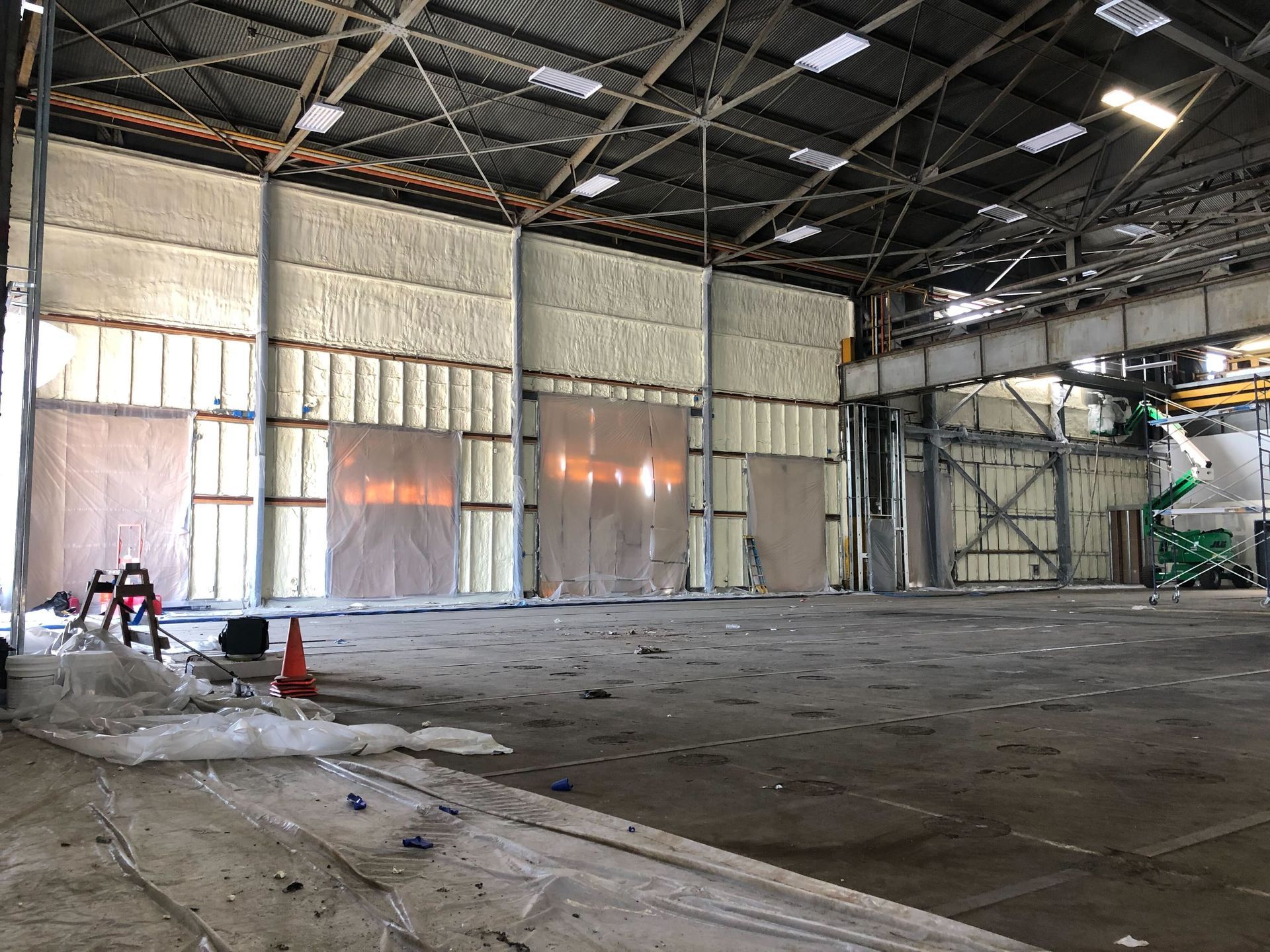 Empty industrial warehouse interior with metal walls, concrete floor, and a few safety cones.