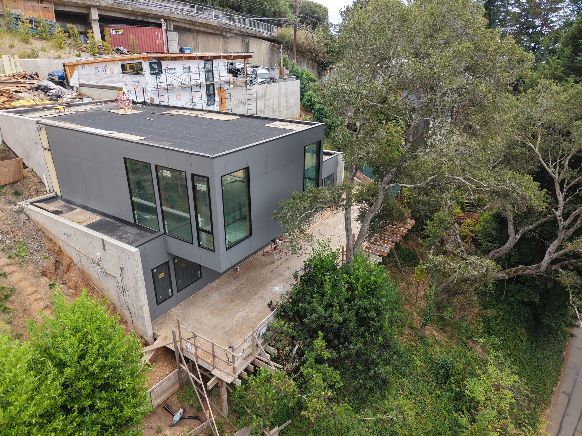 Modern gray house with large windows on a steep hillside surrounded by trees