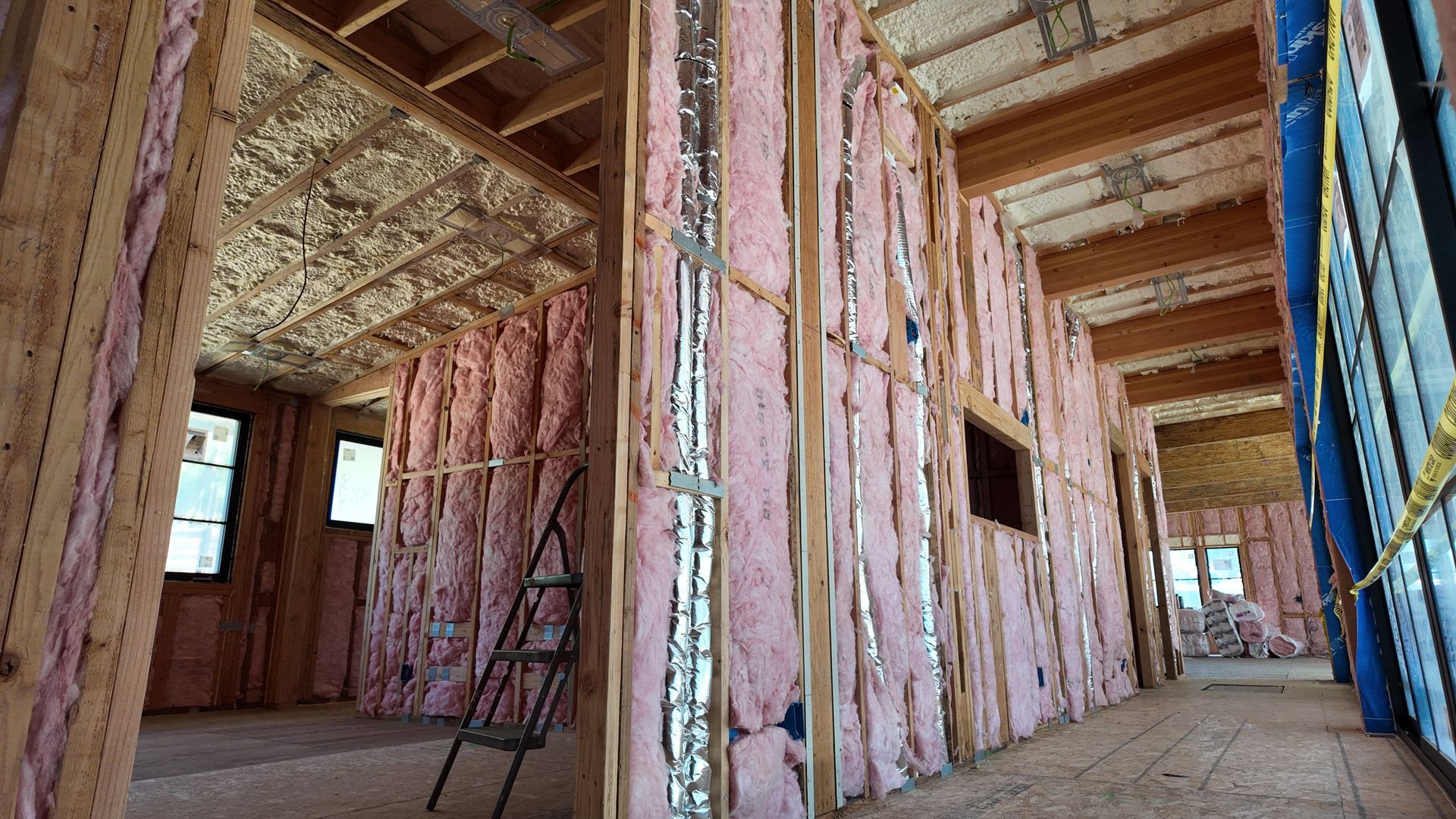 Partially insulated house interior with exposed wooden framing and open doorways