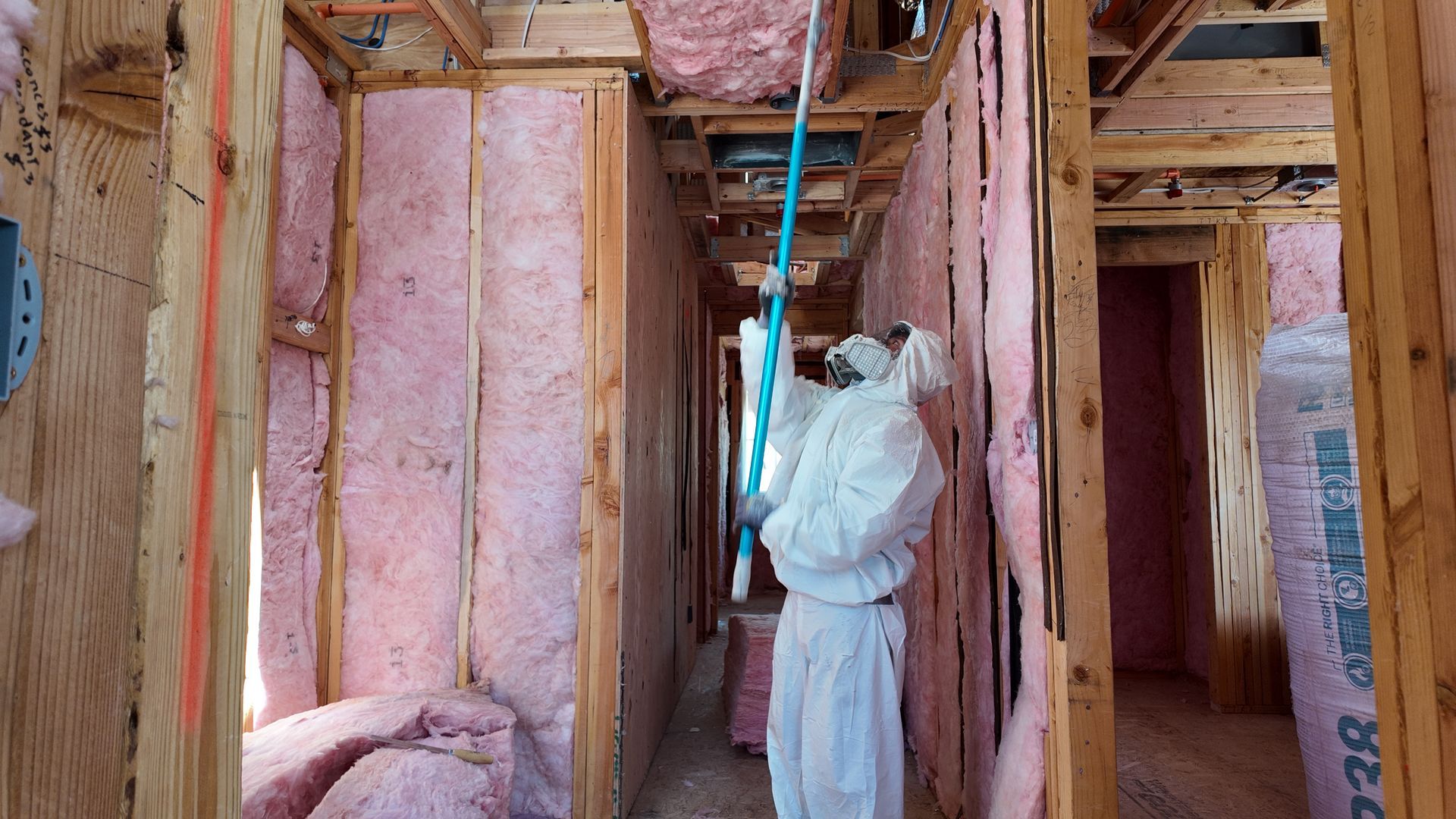 Unfinished room with exposed insulation, two windows, and bare walls under construction