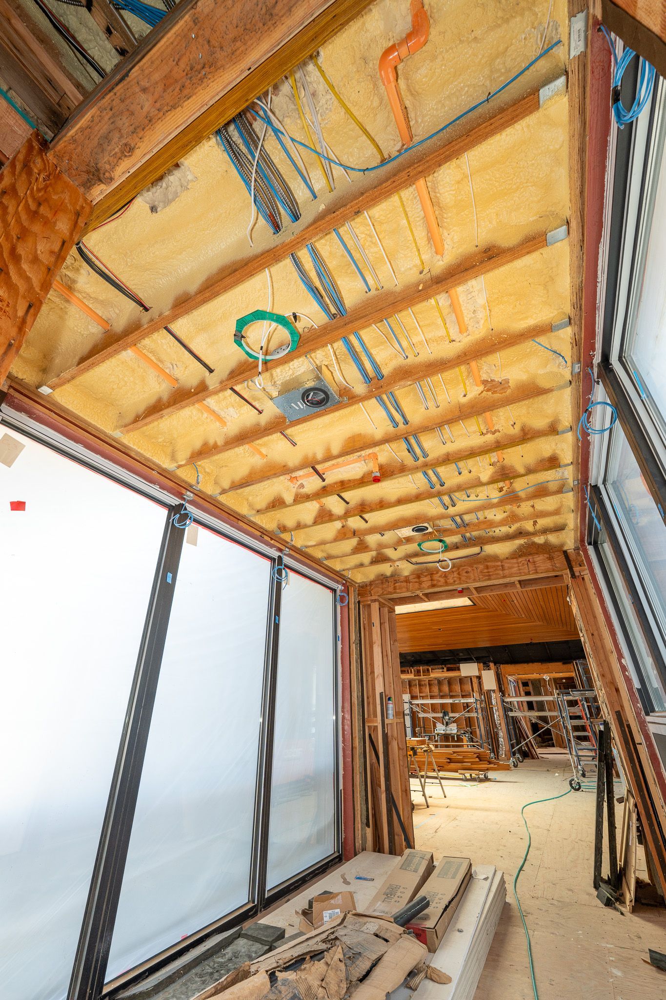 Attic skylight window surrounded by spray foam insulation and exposed wooden framing