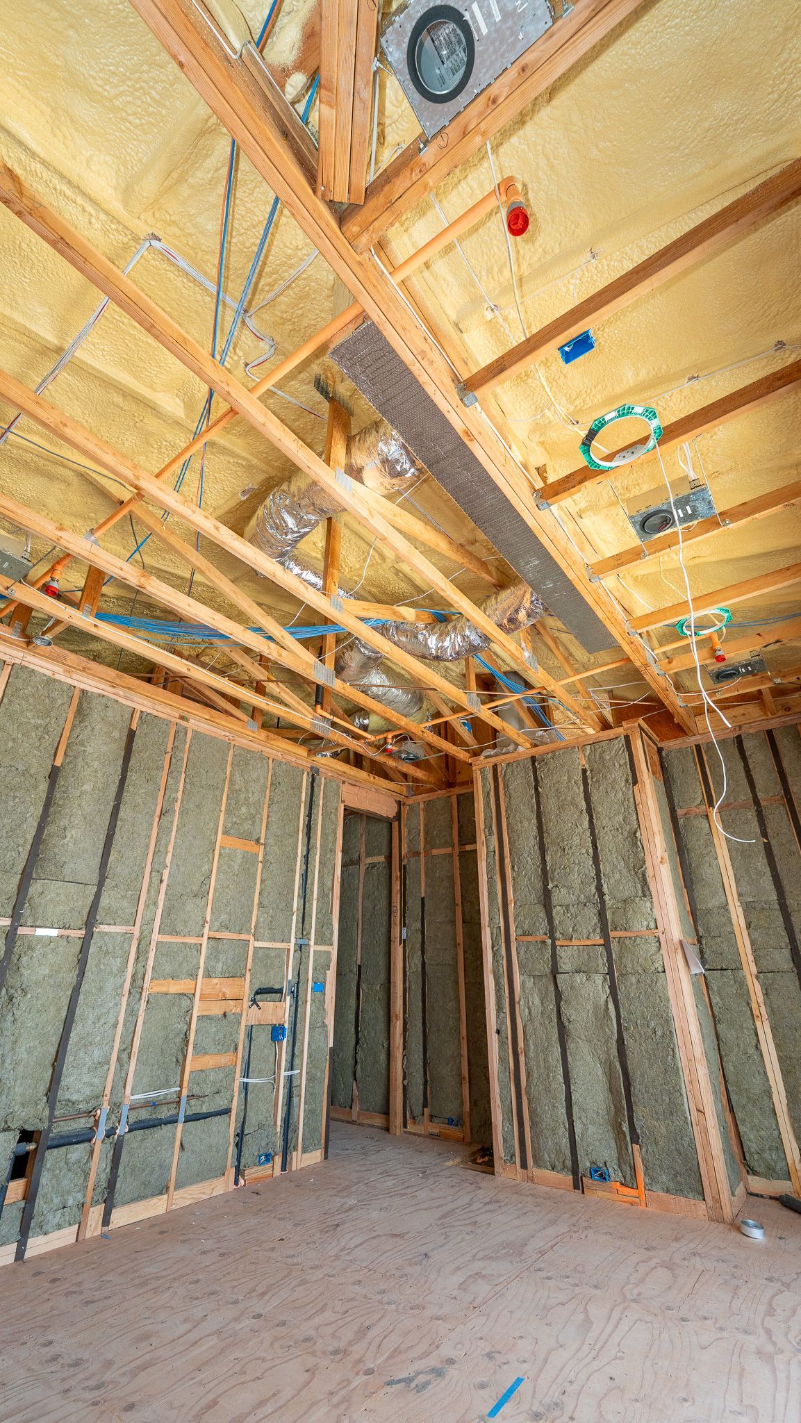 Unfinished room under construction with exposed wood framing, insulation, and concrete block walls.