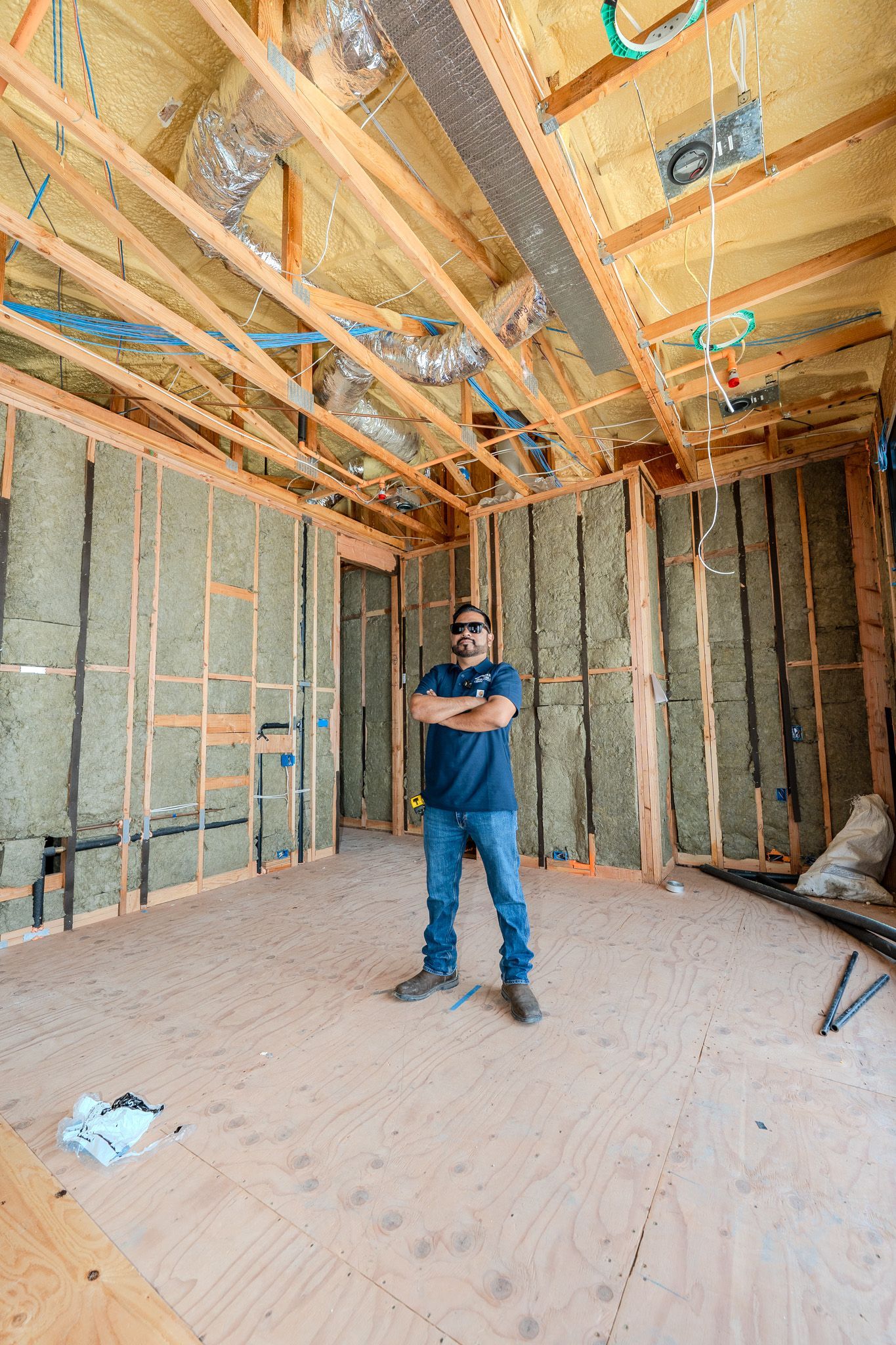 Unfinished room with exposed insulation, two windows, and bare walls under construction