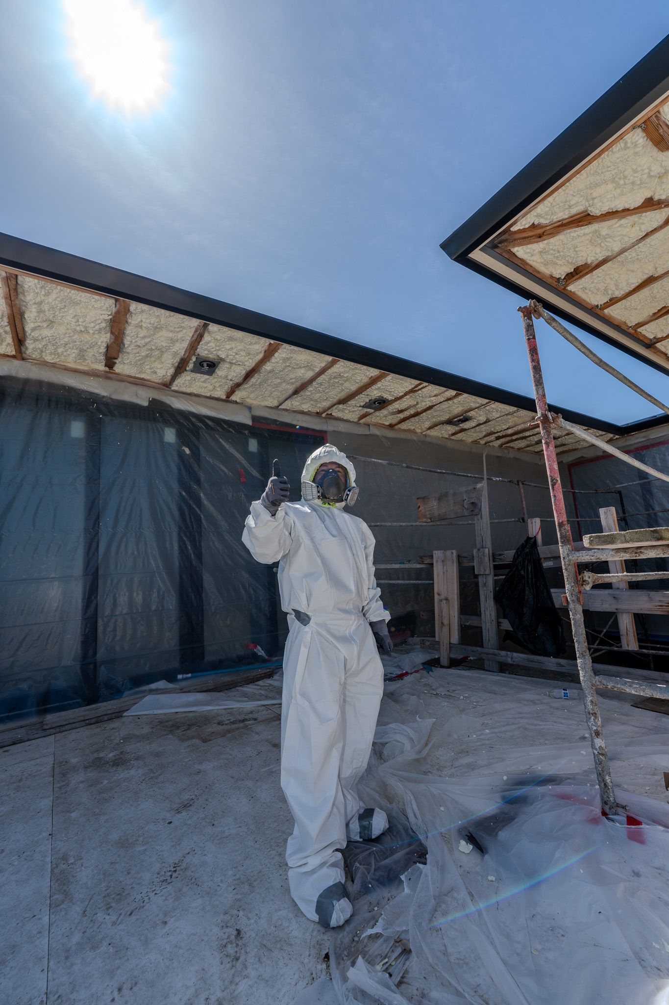 Worker installing insulation boards in an attic with exposed wooden beams