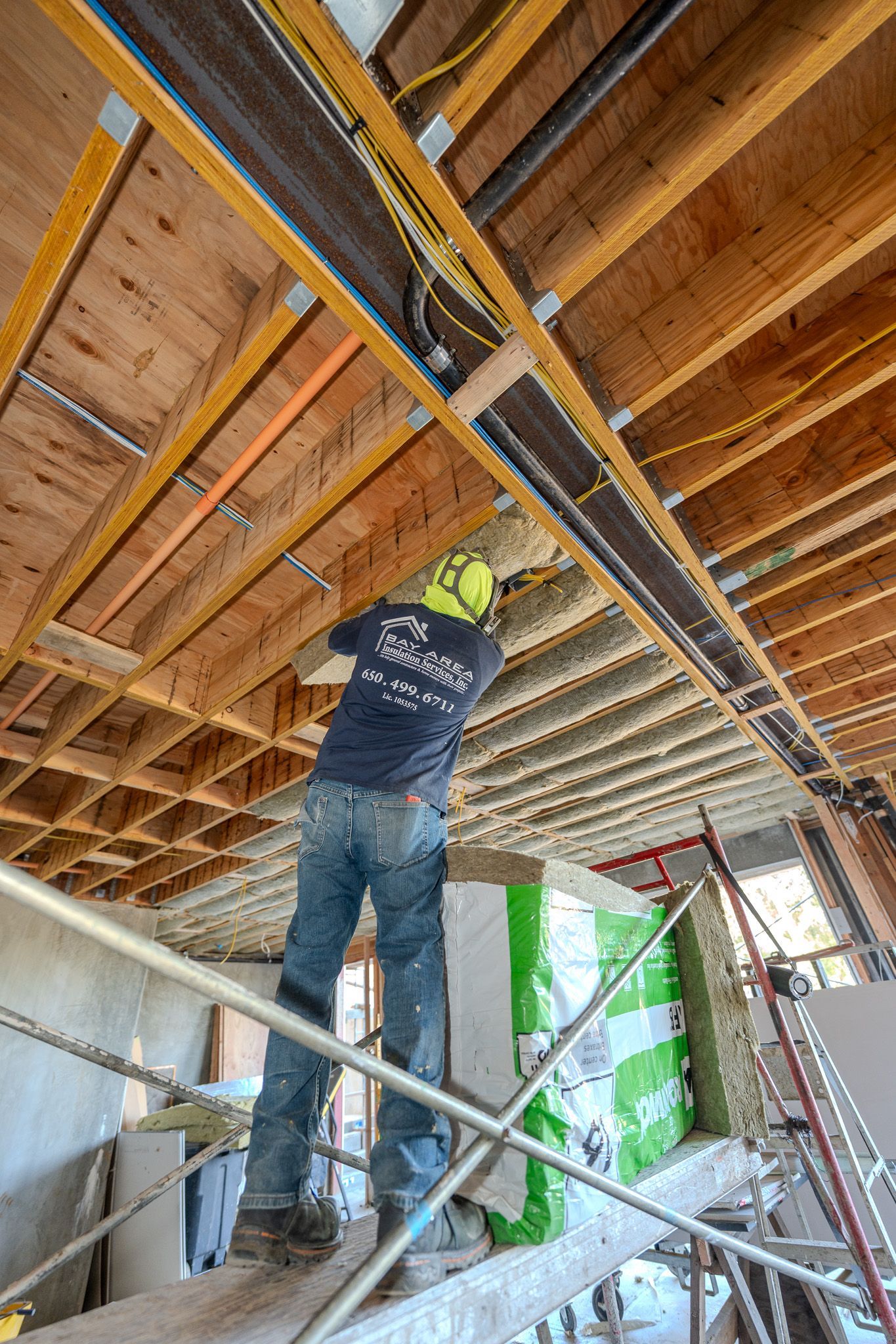 Looking up through a wooden roof opening with insulation and blue sky visible above